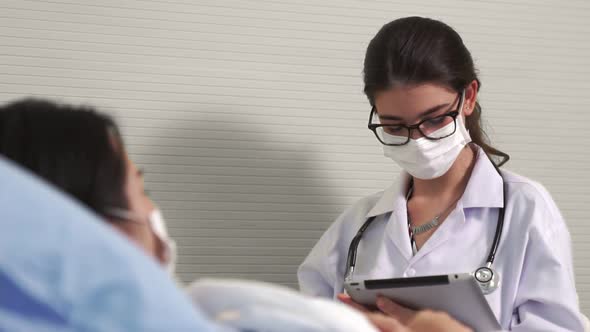 Doctor Wearing Face Mask Proficiently Talks with Patient at Hospital Ward