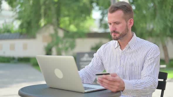 Happy Online Payment on Laptop By Middle Aged Man