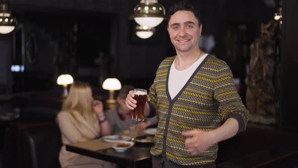 Portrait of Happy Man with Pint of Beer Gesturing Thumb Up Looking at Camera Smiling