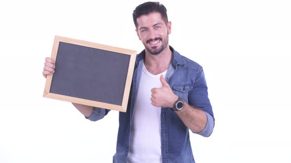 Happy Young Bearded Hipster Man Holding Blackboard and Giving Thumbs Up