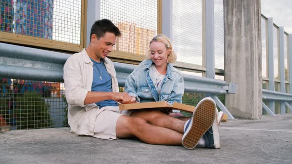 Happy Couple Eating Pizza on City Street