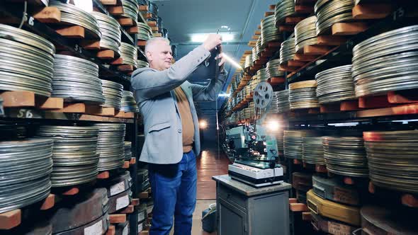 Male Archivist is Inspecting Old Film Tapes