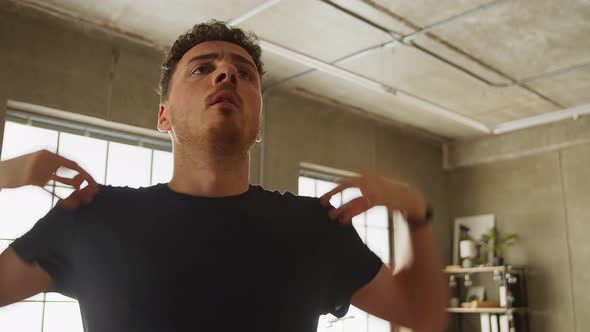 Young Caucasian Man Kneading Body Before Fitness at Home in Living Room