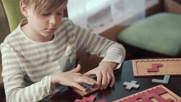 The Boy Collects a Puzzle While Sitting at a Table