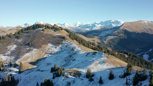 Aerial of green mountain ridge with a thing layer of snow