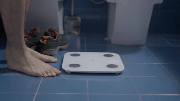 Barefoot Man Weighting Himself in the Bathroom As a Morning Routine  Close Up Shot