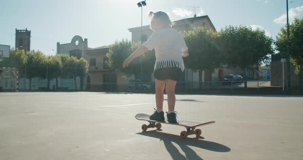 Happy Toddler Girl Learn Ride Skateboard on Sport Field on Summertime Vacation