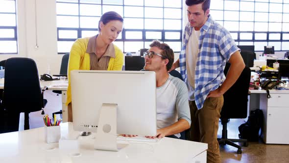 Colleagues looking at computer and discussing with each other