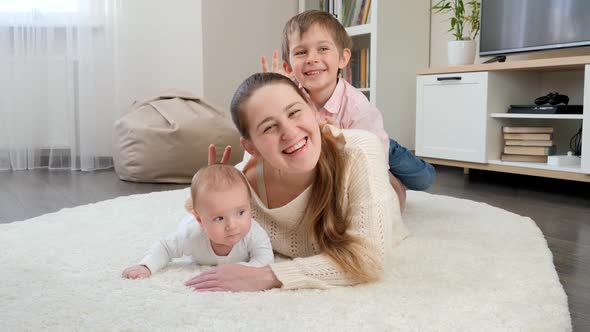 Funny Family Showing v Sign or Making Horns on Photograph in Living Room