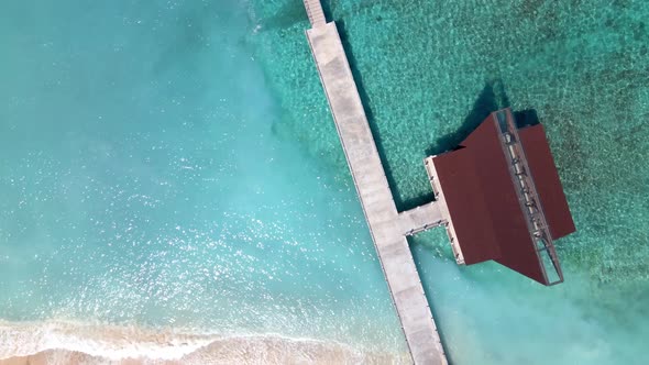 Aerial top down of transparent ocean water in Lombok and wooden jetty during sunny day.Indonesia,Asi