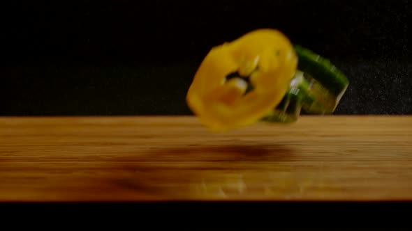 Bell pepper slices falling on a wooden surface, Ultra Slow Motion