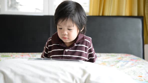 Asian Baby Using Tablet On Bed