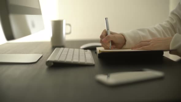 Student Searching Information On Computer And Writing Notes