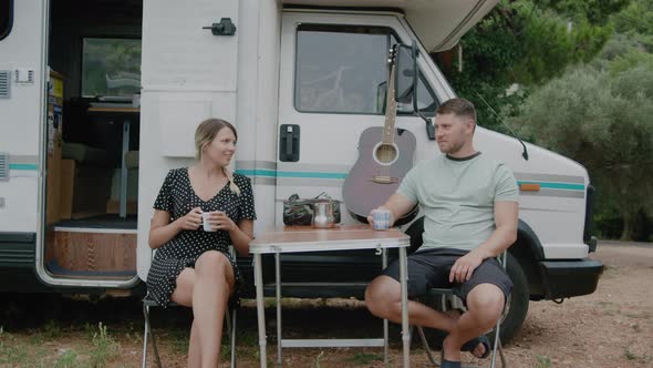 Young adult Couple by Camper van drinking coffee while camping on road trip in Montenegro