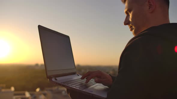 Hipster Man with a Laptop on the Edge of the Roof. Freelancer at Work. Wireless Mobile Internet. He