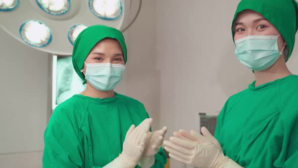 Asian medic team of surgeons doctor and nurses suture feel glad and clap hands after success surgery