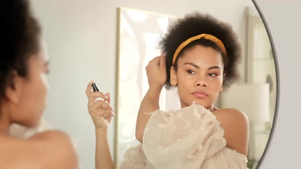 African american woman applies hair spray care balm styling cosmetics on damaged dry ends