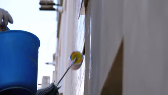 Industrial Climber Primers the Wall of Building with a Roller. Slow Motion