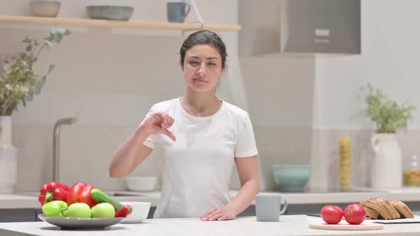 Indian Woman Showing Thumbs Down While Standing in Kitchen