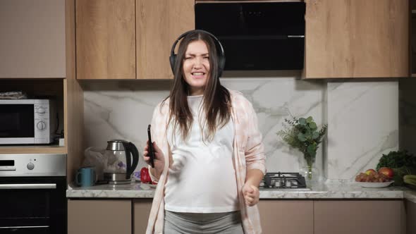 Pregnant Woman Sings and Dances with Phone and Headphones