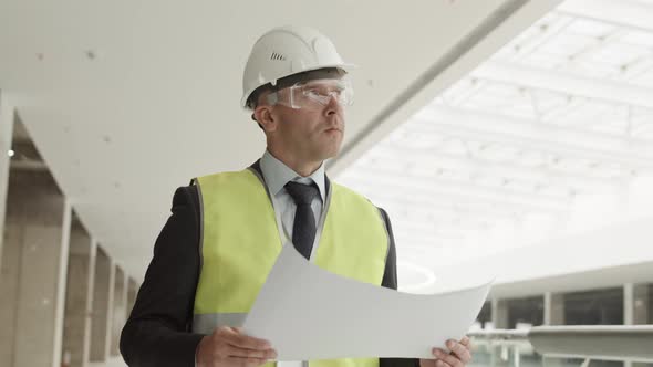 Builder with Paper Supervising Construction Site