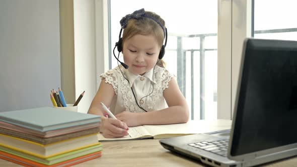 Little Girl Communicates with a Teacher Via the Internet. Online Training During Quarantine.