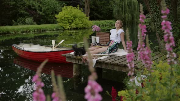 Woman relaxes on wooden jetty at botanical garden with pink flower in foreground