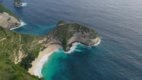 Aerial POI of tropical sandy beach nestled in lush, green cliffs