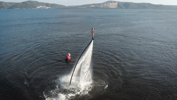 Energetic Man Flying on Jet Pack Over Water