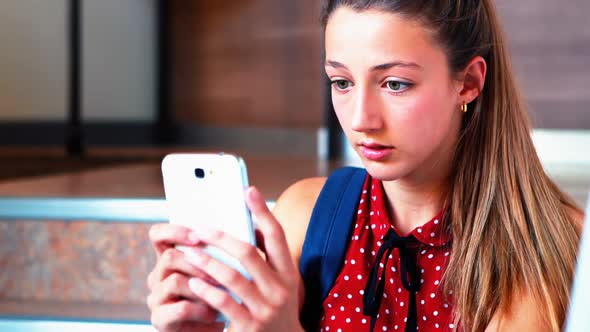 Schoolgirl sitting on staircase and using mobile phone