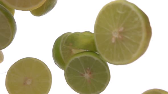 Super Closeup of the Halves of Ripe Limes Falling Down on the White Background