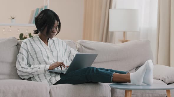 Young Focused Businesswoman Freelancer Typing on Laptop Working Remotely at Home Using Computer