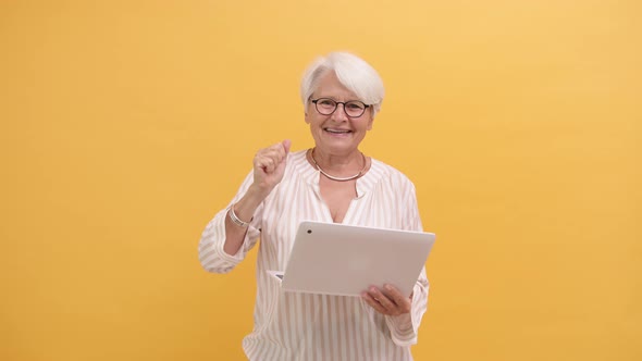 Happy Senior Lady Winning the Online Lottery. Lifting Her Fist in Excitement