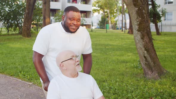 African-American caregiver and old disabled man in a wheelchair. Nurse and patient.