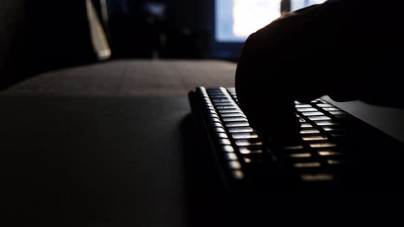 Hands Are Typing On The Keyboard Against The Background Of The Window And The Setting Sun