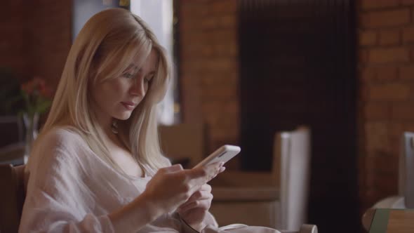 Blond Woman Using Mobile Phone in Cafe