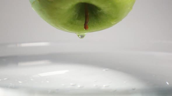 Drop of Water Falling Down From Apple Into Water