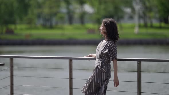 Adult Woman is Enjoying Freedom and Independence Walking on Shore of Lake at Sunny Day