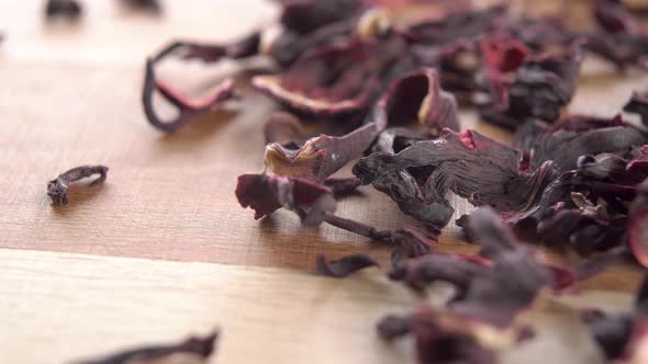 Red dry hibiscus tea on a wooden surface. Pink dried flower petals