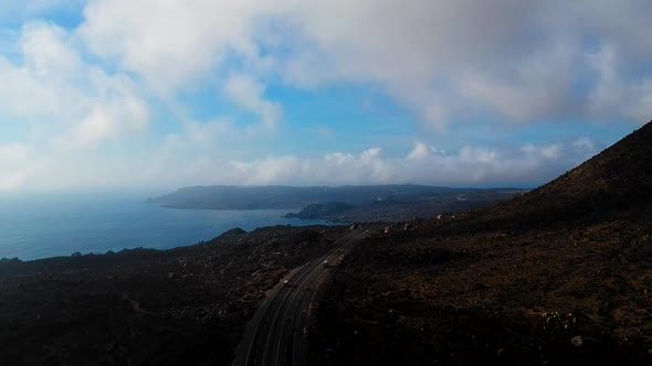 Aerial of highway next to the sea, cliffs and rocks