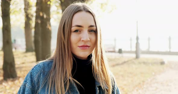 Portrait of Young Attractive Female Who Smiling and Looking at the Camera on Autumn Park. Cheerfully