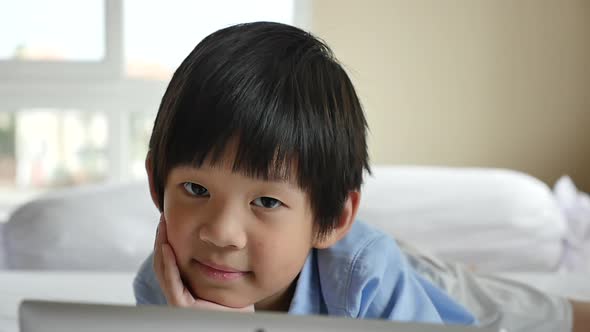 Cute Asian Boy Lying In Bed And Using Laptop On White Bed Slow Motion