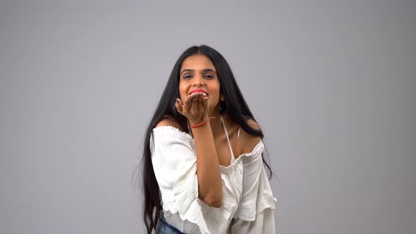 A beautiful and attractive Indian girl giving flying kisses to the camera