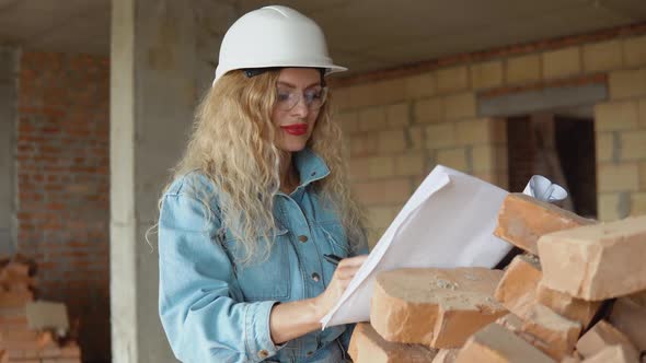 Female Architect Reads the Architectural Plan for the Construction of the House and Makes Marks in