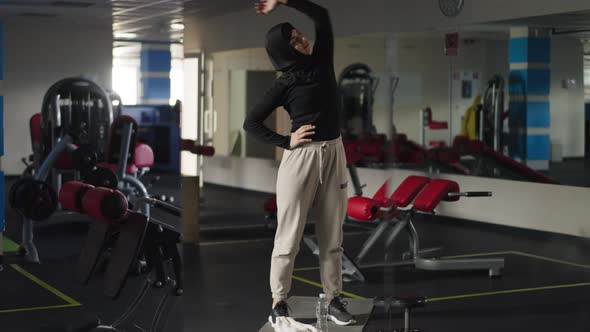 Wide Shot Positive Confident Middle Eastern Woman in Hijab Stretching Neck and Hand Muscles Smiling