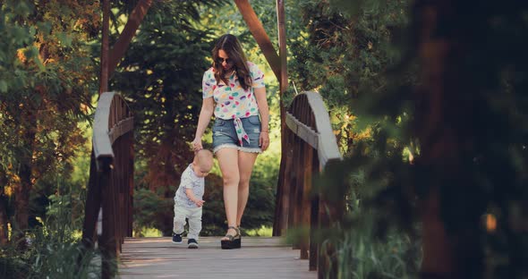 Korean Woman Walks with Her Young Son in the Summer in the Park