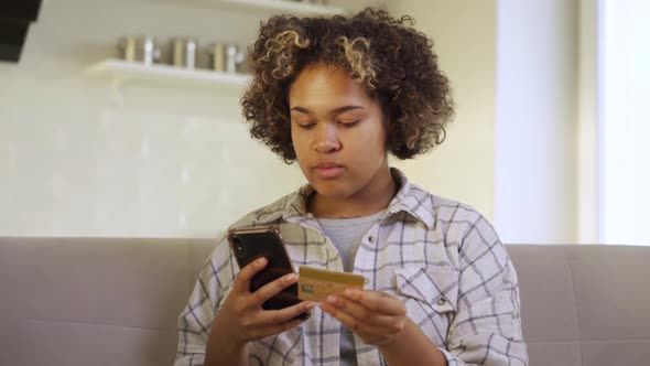 A Young AfricanAmerican Woman Pays Through Her Smartphone at Home