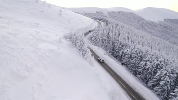 Drone Chasing Silver SUV Speeding Uphill on Winter Road Aerial View