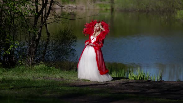 Sexy Blonde Woman is Wearing Extravagant Mediaeval Dress is Posing on Shore of River in Forest