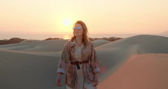 Stylish Woman in Glasses Looking Around Desert Landscape at Sunset